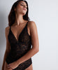 A woman wearing a black lace bodysuit with a deep V-neckline and thin straps.