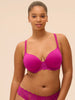Woman wearing a pink bra and underwear set against a beige background