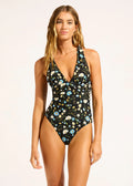 Woman wearing a floral one-piece swimsuit on a plain background