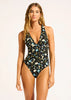 Woman wearing a floral one-piece swimsuit on a plain background