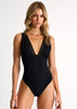 Woman wearing a black swimsuit with a plunging neckline on a white background