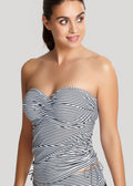 Woman wearing a strapless black and white striped tankini top against a plain background