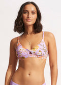 A woman wearing a purple floral Seafolly bikini top with a twist front detail.