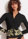 A woman wearing a long sleeve black rash guard with floral print detailing on the lower hem.